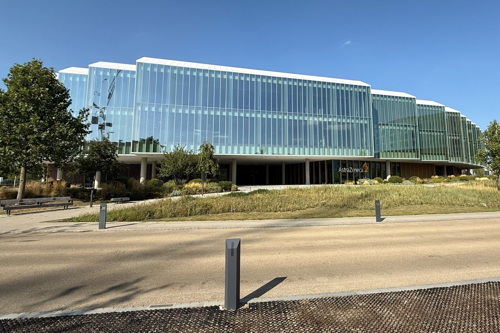 Edifício envidraçado da AstraZeneca em Cambridge, na Inglaterra, com jardins em primeiro plano.