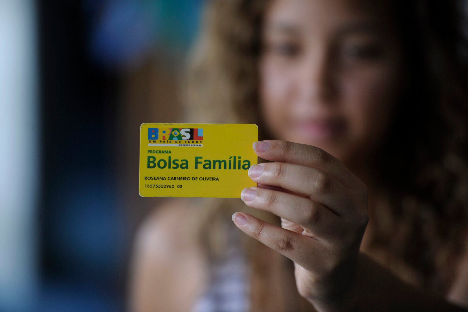 Cartão do Bolsa Família segurado por uma mulher, em fotografia de arquivo.