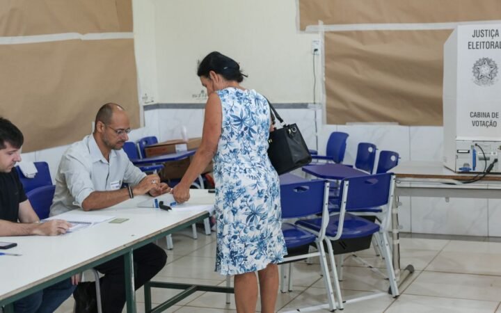 Eleitora se identifica diante de mesários em uma seção de votação