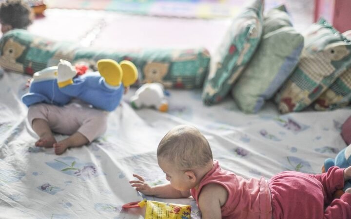 Bebês brincam em um ambiente com colchonetes e almofadas
