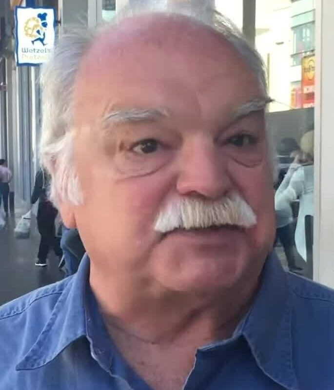 Richard Riehle, de camisa azul e bigode branco, em registro de 2016
