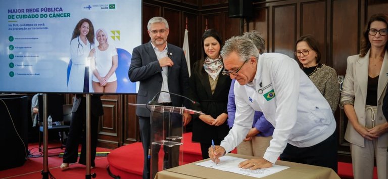 Ministro Alexandre Padilha assina documento no anúncio de medicamentos oncológicos.